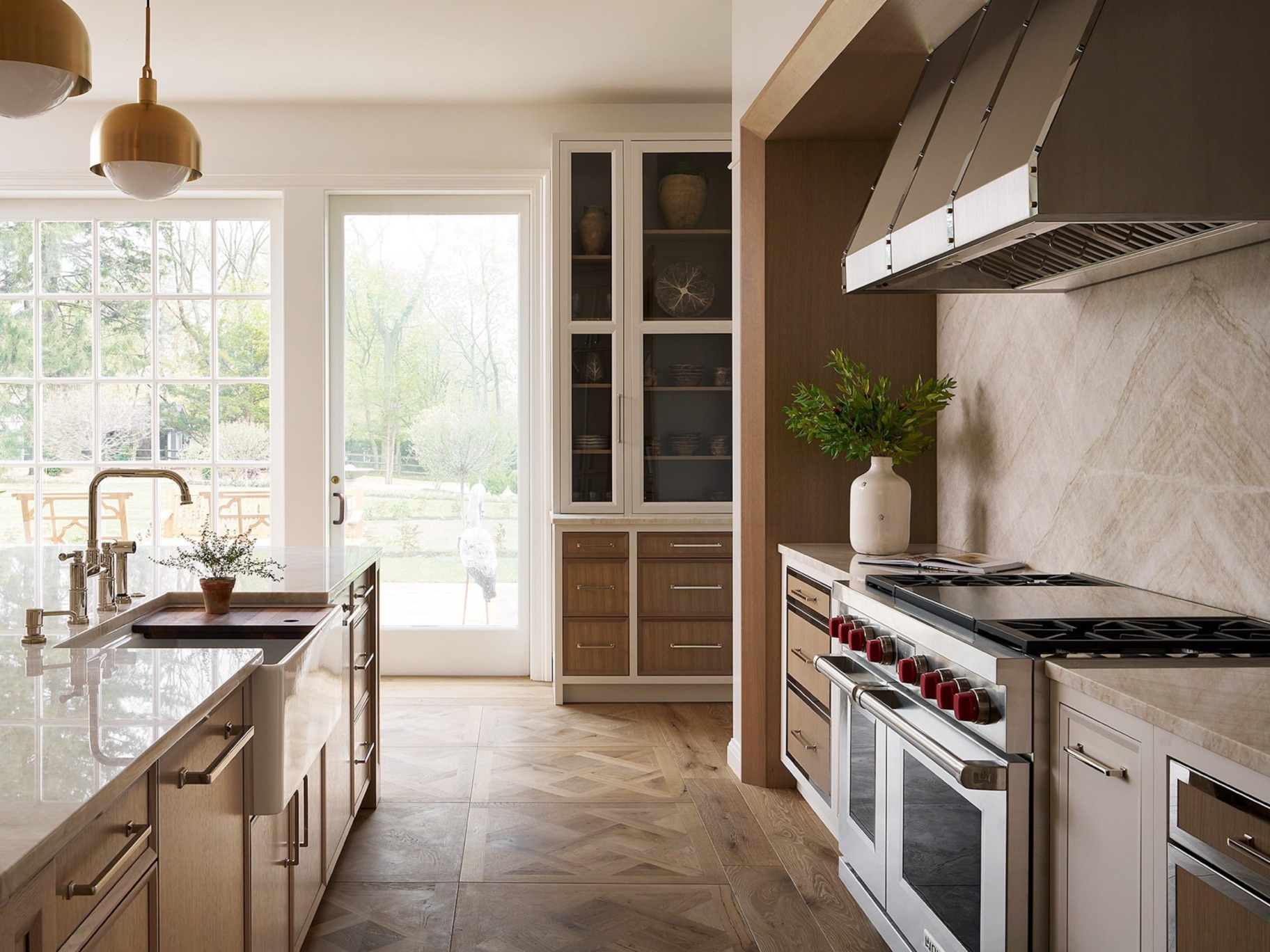 Warm contemporary kitchen with custom cabinetry and brass pendants